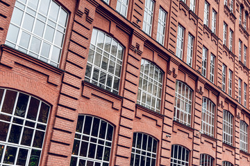 The facade of a classic red brick building with large windows. Brick architecture of a prestigious area. Expensive real estate.