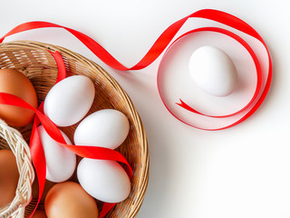 Healthy food idea concept, Isolated gift set of fresh duck and chicken eggs in basket with red ribbon decorated on white table background-top view