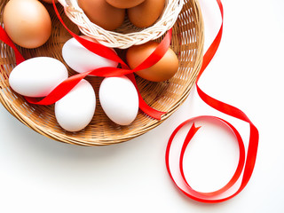 Healthy food idea concept, Isolated gift set of fresh duck and chicken eggs in basket with red ribbon decorated on white table background-top view