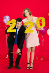 A couple celebrate new year 2020 with a lot of ballons in red background