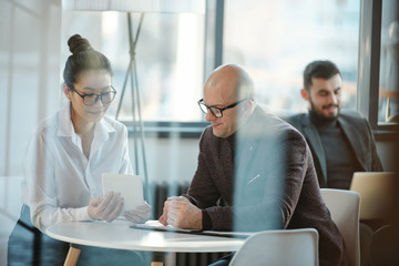 Asian businesswoman making presentation to mature colleague at working meeting
