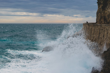 Fisherman silhouette and huge sea waves