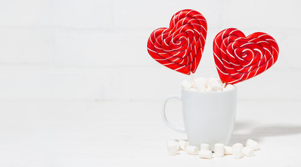 candy on a stick in the form of hearts in a white cup