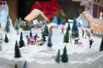 Little toy Christmas miniature with people skating and playing snowballs