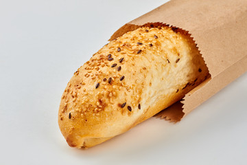 French baguette with sesame and flax seeds. French bread in vintage paper bag on white background. Healthy eating concept.