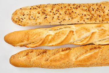 Three fresh baguettes close up. White freshly baked bread on white background. Food and nutrition.