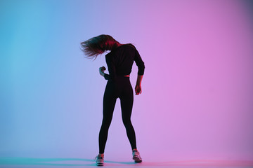 Charismatic young creative dancer posing in studio against colorful background. Sporty woman dance and her hair follow her head