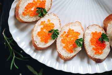 Canapes with salmon red caviar on a dark background