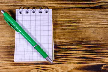Opened small notepad and ball pen on a wooden table. Top view