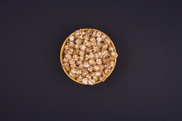 Caramel sweet popcorn bowl isolated on black background top view. Top view, copy space, flat lay