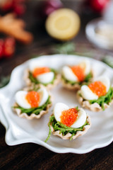 Quail eggs with red caviar on a basket of spinach dough. Served on a dark board