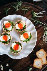 Quail eggs with red caviar on a basket of spinach dough. Served on a dark board