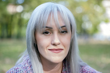 Outdoors portrait of a woman making funny faces. Silver hair.