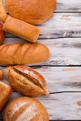 Different types of bread, top view. Bread loaves on retro wooden background with copy space. Bakery concept.