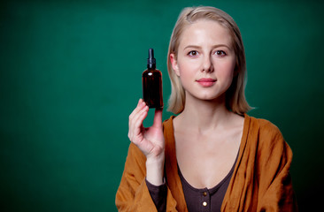 blond woman with black bottle on green background
