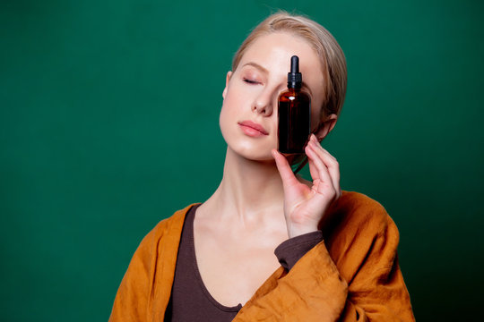 Woman Holds Black Bottle On Green Background