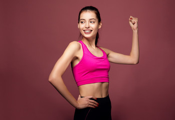 Fototapeta na wymiar Portrait of a cheerful fitness woman flexing biceps.