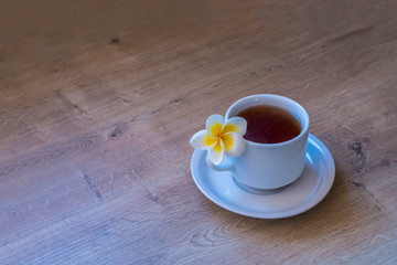 A cup of tea and an exotic flower on wooden background.