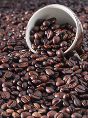Roasted coffee beans, background. Vertical orientation. Fresh aromatic dark coffee beans and an espresso cup.