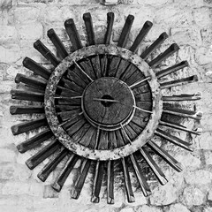 Old wooden wheel mill on the wall.