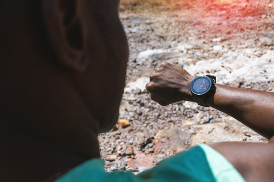 Close Up Mixed Race Man's Hand Looking Smart Watch And Navigation Compass Application For See Path To Goal Trail Race. Healthy Lifestyle, Technology And Sport Concept.