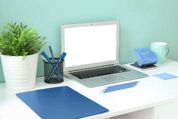 Comfortable workplace with modern laptop near blue wall