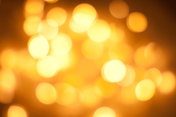 Obraz premium Glowing and festive gold light circles created from in camera and lens bokeh. Christmas fairy lights defocused giving a blurred effect. Background for design.