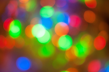 Fototapeta premium Glowing and festive colored light circles created from in camera and lens bokeh. Christmas fairy lights defocused giving a blurred effect. Background for design.