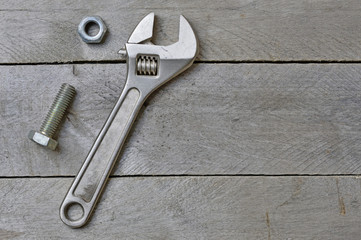 adjustable wrench and bolt on a wooden background. copy space.