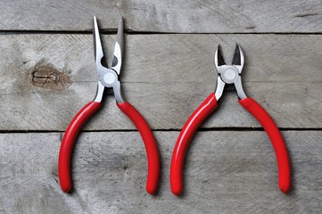 nippers and pliers with red handles on a wooden background. copy space.