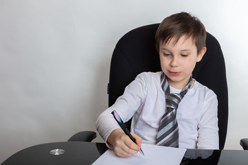 Close up of a cute brunette boy Presents being a director. The boy writes a letter In a white...