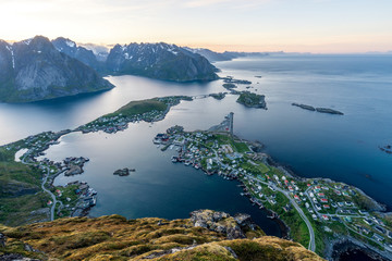 From top of the famous Reinebringen overlooking the city of Reine in Lofoten,Norway during the midnight sun. Mountains and island view in the beautiful landscape. Nature and travel concept.