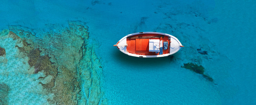 Aerial drone top down ultra wide photo of traditional fishing boat docked in world famous paradise beach of Mykonos island, Cyclades, Greece