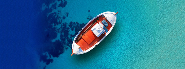 Obraz premium Aerial drone top down ultra wide photo of traditional picturesque wooden fishing boat in Crete island beach with turquoise sea, Greece