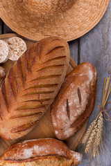Bread and wheat ears on rustic table. Whole wheat bread and wheat spikelets on wooden background. Flat lay, top view.