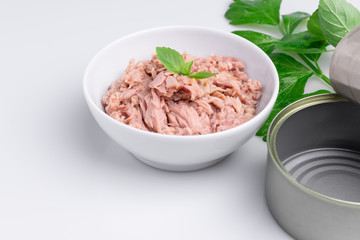 Canned tuna in a white bowl, isolated on white; empty open tuna tin on a white background; copy space, soft light, studio shot