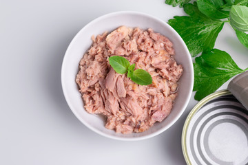 Canned tuna in a white bowl, isolated on white; empty open tuna tin on a white background; copy space, soft light, studio shot