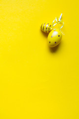 Easter decoration, two yellow decorative eggs stitched together with ribbons on a bright yellow background