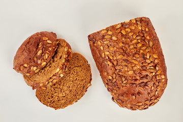 Slices of cereal bread, top view. Loaf and slices of whole wheat bread isolated on white background. Food concept.
