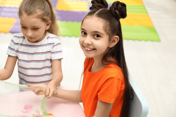 Happy girls playing with slime at table indoors