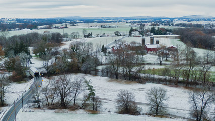 Fototapeta na wymiar Pennsylvania aerial landscape in first snow, traditional farm and covered bridge, Keller's Mill in Lancaster County, PA