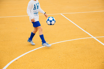 Boy playing soccer on the yellow court