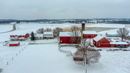 Farm in winter, red house and barn in white snow landscape