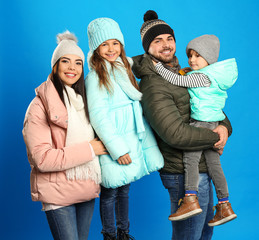 Happy family in warm clothes on blue background. Winter vacation