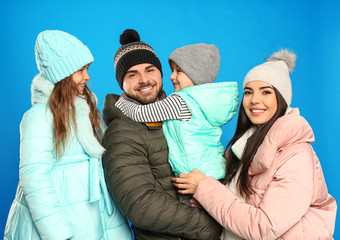 Happy family in warm clothes on blue background. Winter vacation