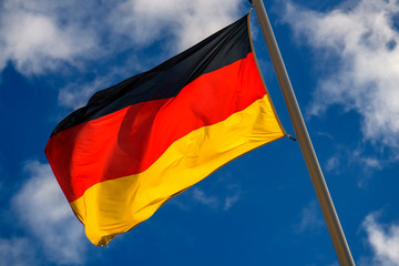 State flag of Federal Republic of Germany against a blue sky.