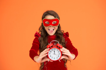 Right time is now. Party girl show clock time. Small child in carnival mask hold alarm clock. 12...
