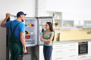 Fototapeta na wymiar Male technician talking with client near refrigerator in kitchen