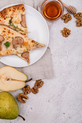 pieces of fruit pizza on white plate decorated with pears, honey and walnuts vertical orientation