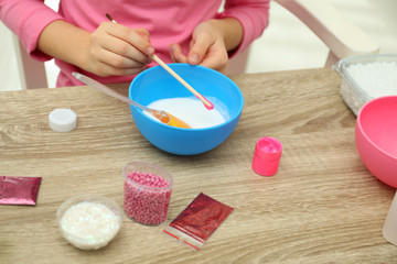 Little girl making homemade slime toy at table, closeup